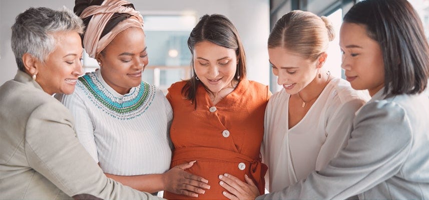 women standing around pregnant woman